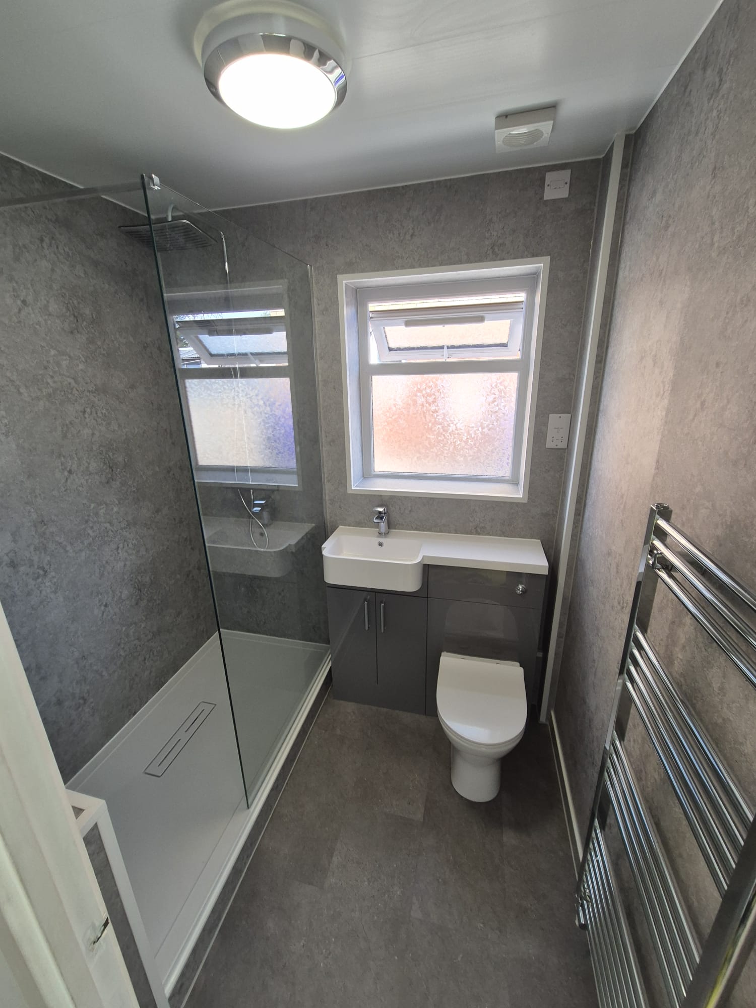 Compact grey shower room installation in Stoke-on-Trent with walk-in glass screen and combined vanity