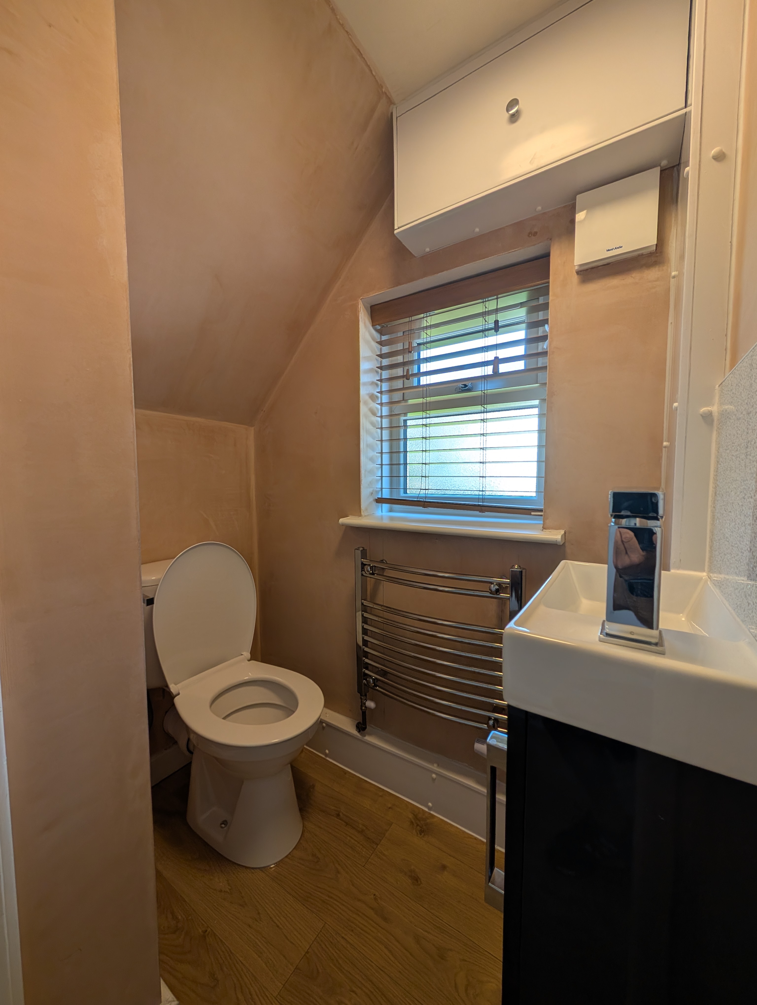 Under-stairs cloakroom refit in Stoke-on-Trent with fresh plaster, chrome towel rail and compact black vanity unit